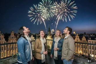 Groupe d'adultes sur une terrasse de toit à Lille regardant le feu d'artifice avec la Grand Place en arrière-plan